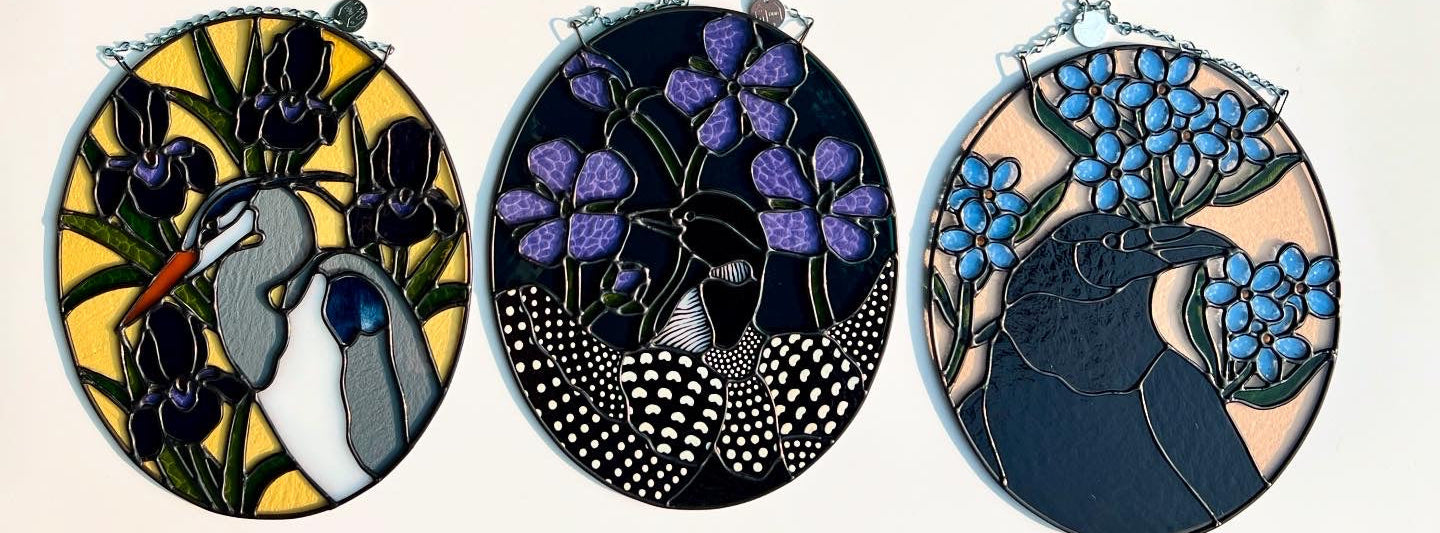 Set of three oval stained glass pieces with various birds and floral designs on a white background.