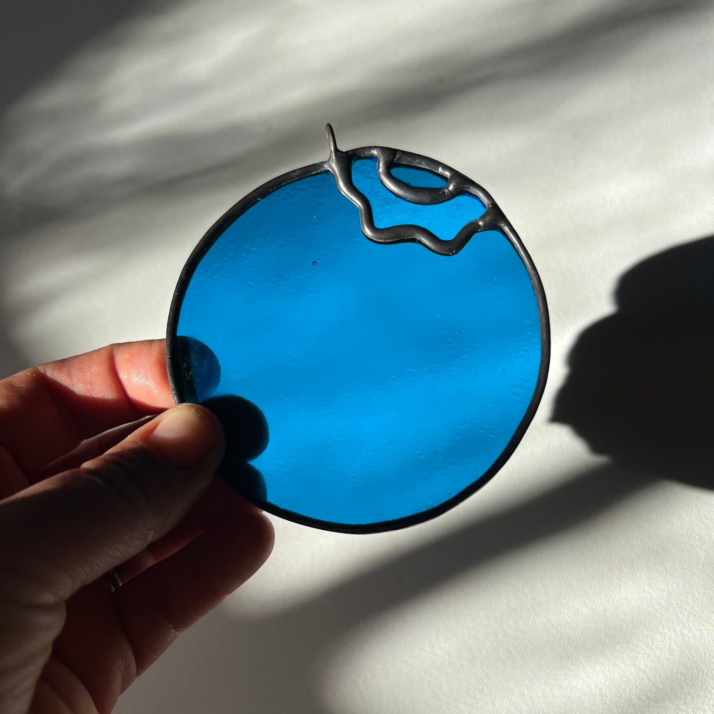 a hand holding a stained glass blueberry
