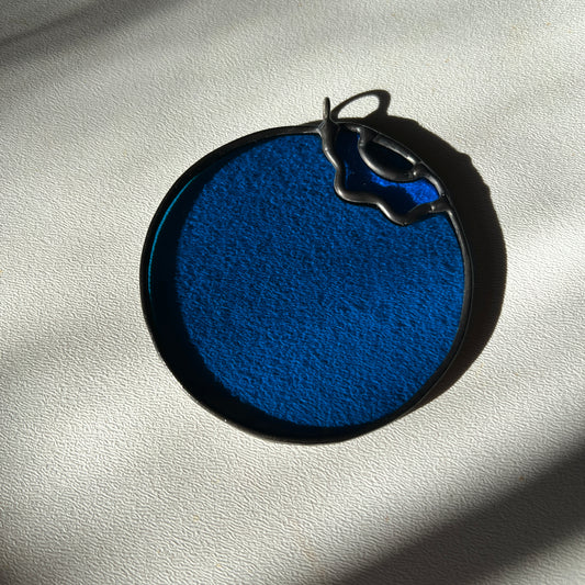a stained glass blueberry resting on a white surface