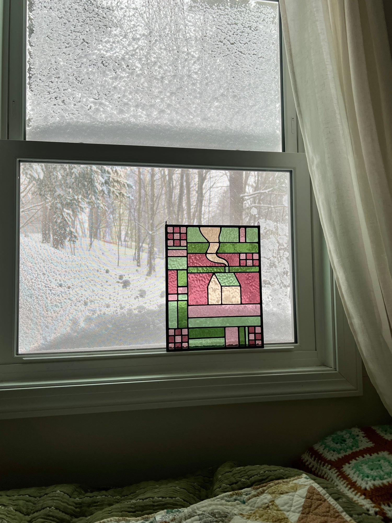 Stained glass panel in a window with a snowy outdoor view