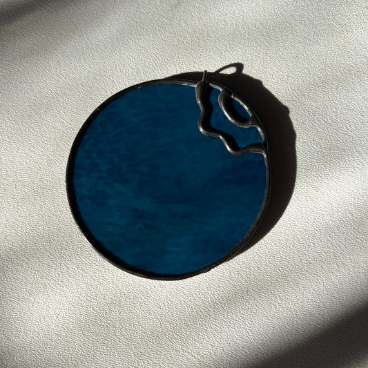 a stained glass blueberry resting on a white surface