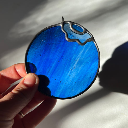 hand holding a blue wispy stained glass blueberry