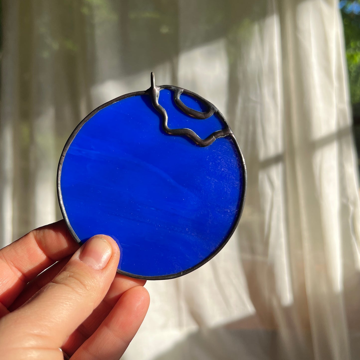 a hand holding a little stained glass blueberry