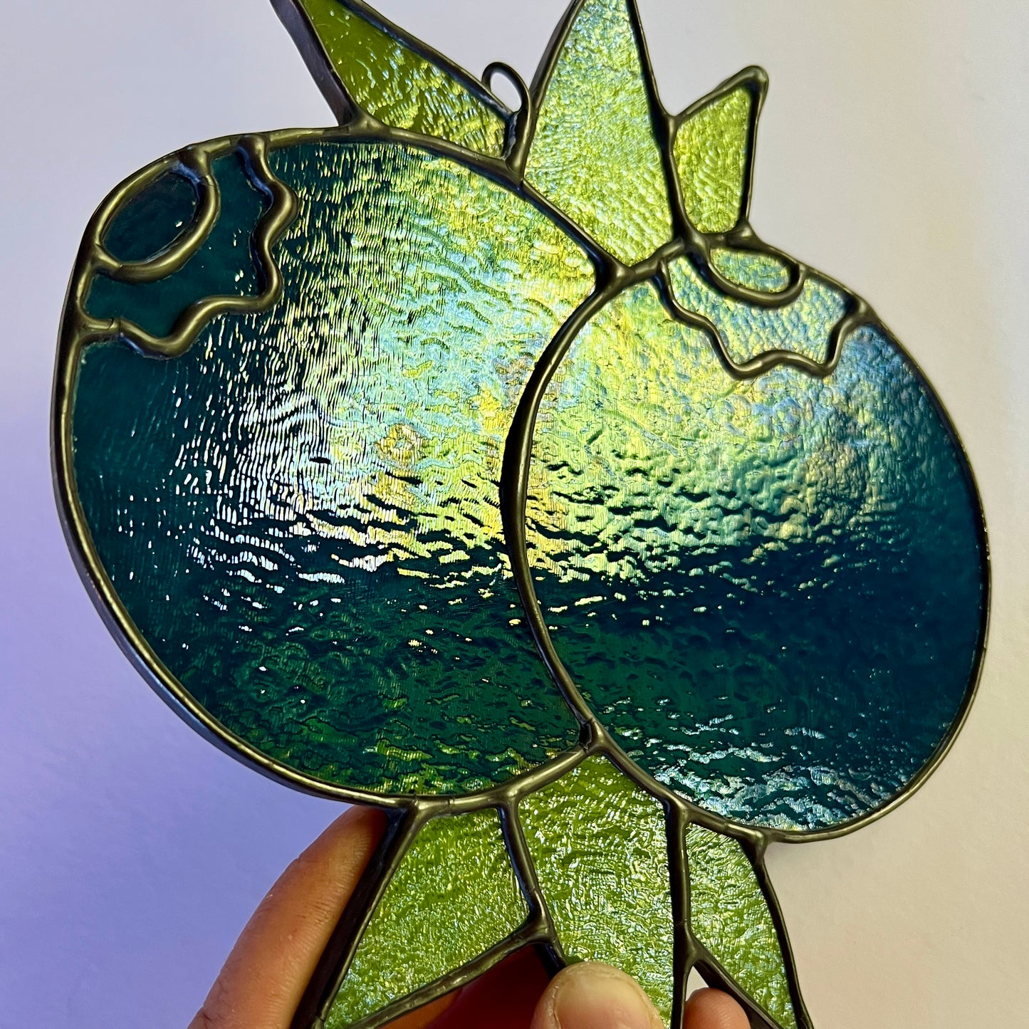 close up of a stained glass blueberry suncatcher showing stains on the surface of the blue glass