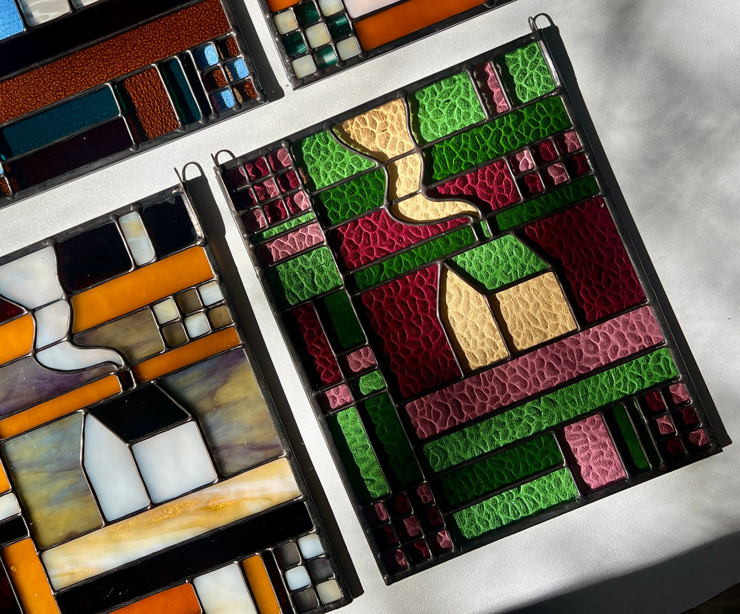 Stained glass panels with textile inspired cozy home designs on a white surface