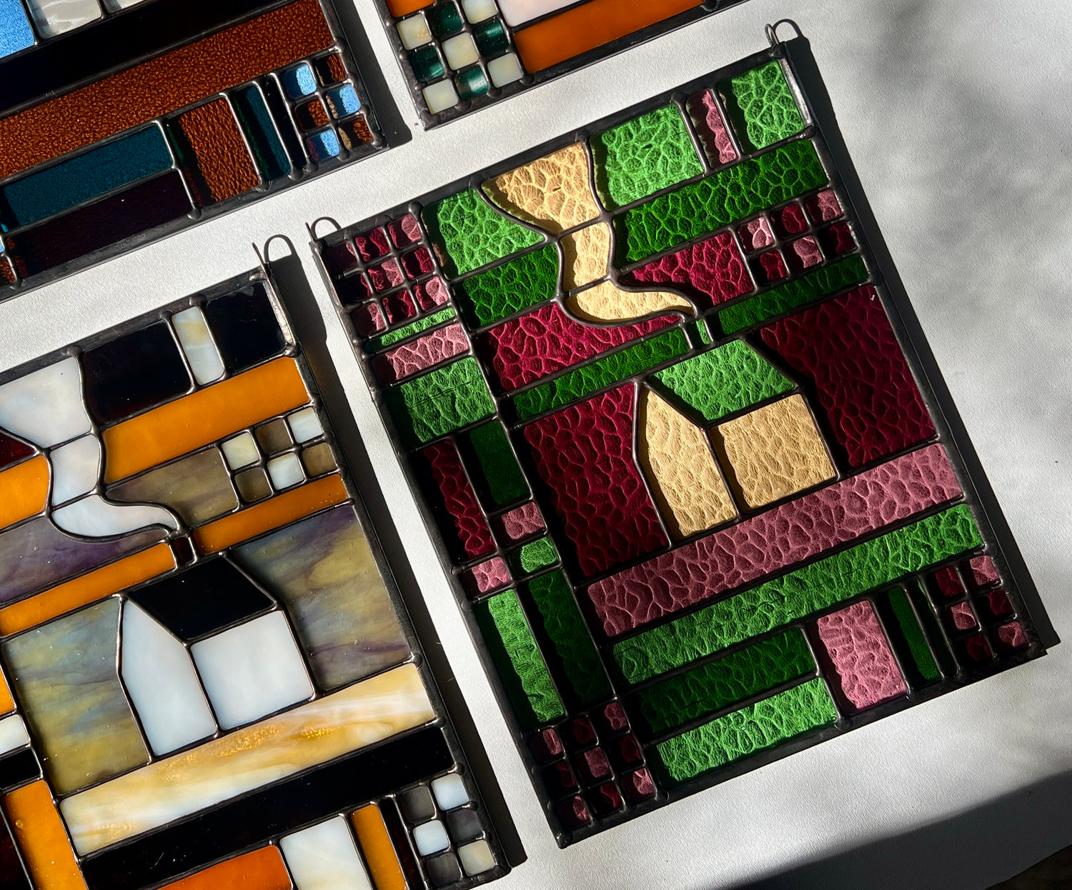Stained glass panels with textile inspired cozy home designs on a white surface