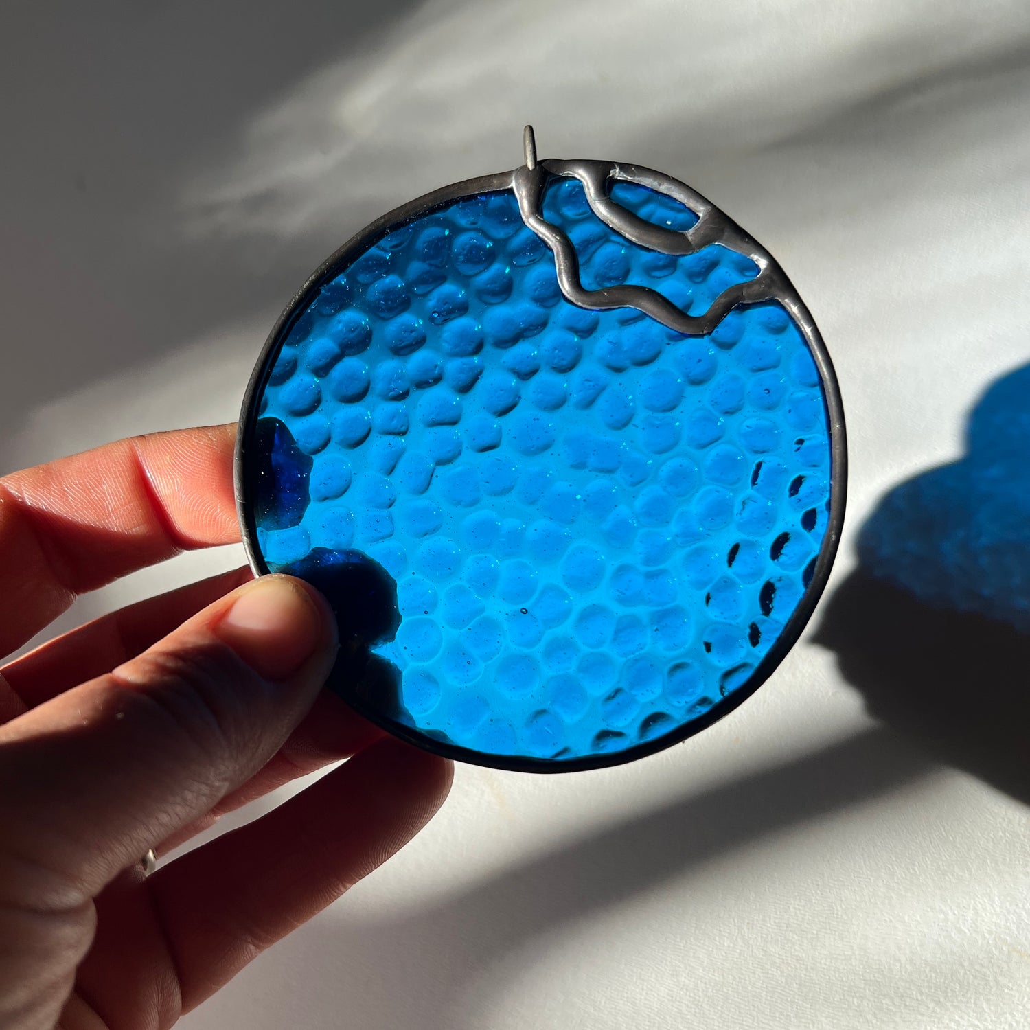 hand holding a textured stained glass blueberry