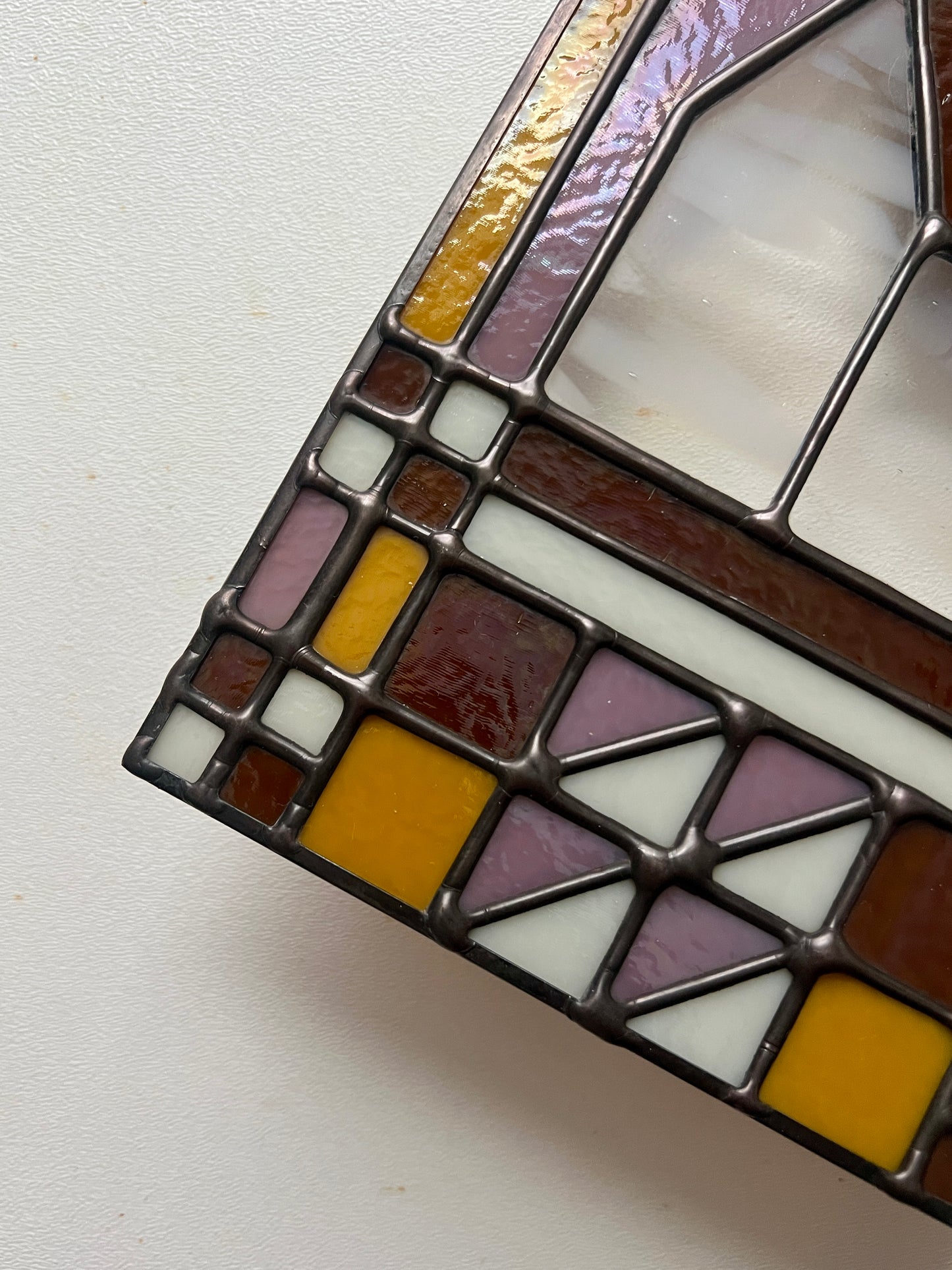 Close up of smooth solder lines on a textile inspired stained glass panel, held above a white backdrop