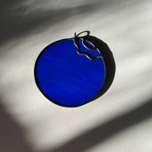 a small stained glass blueberry resting on a white background