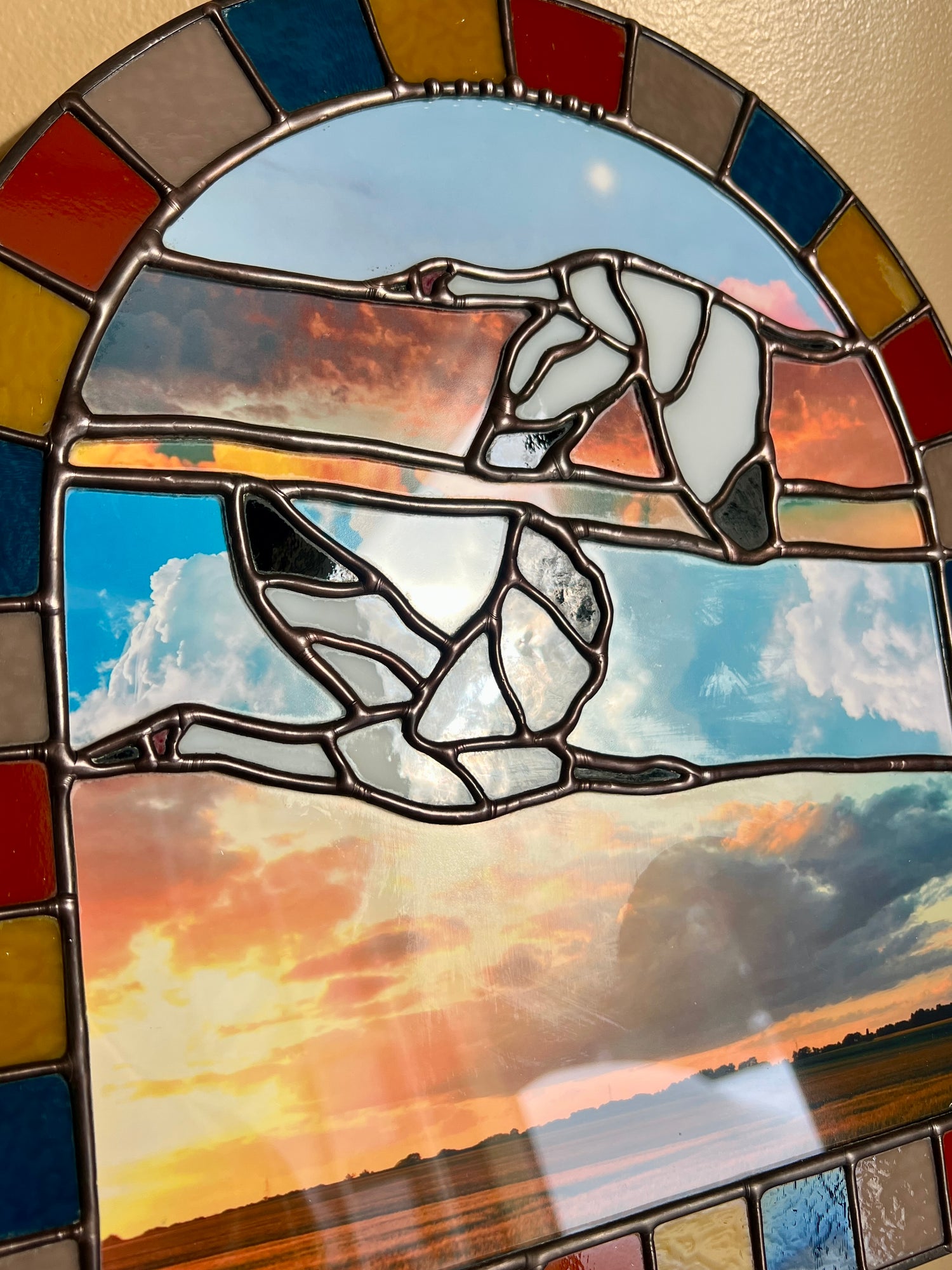 Stained glass panel with a landscape design created by collaged photographs and two cranes flying