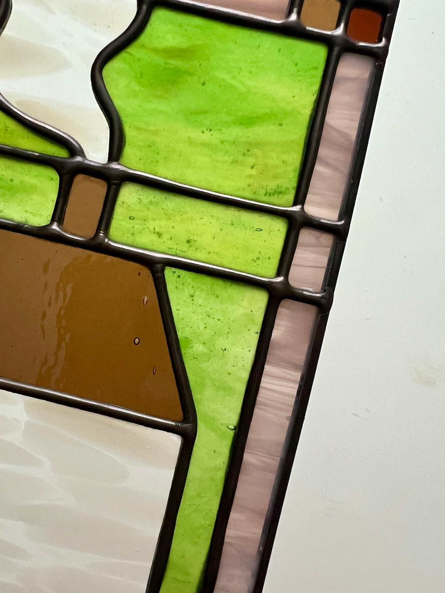 Close-up of a stained glass panel with green and brown colors on a white background