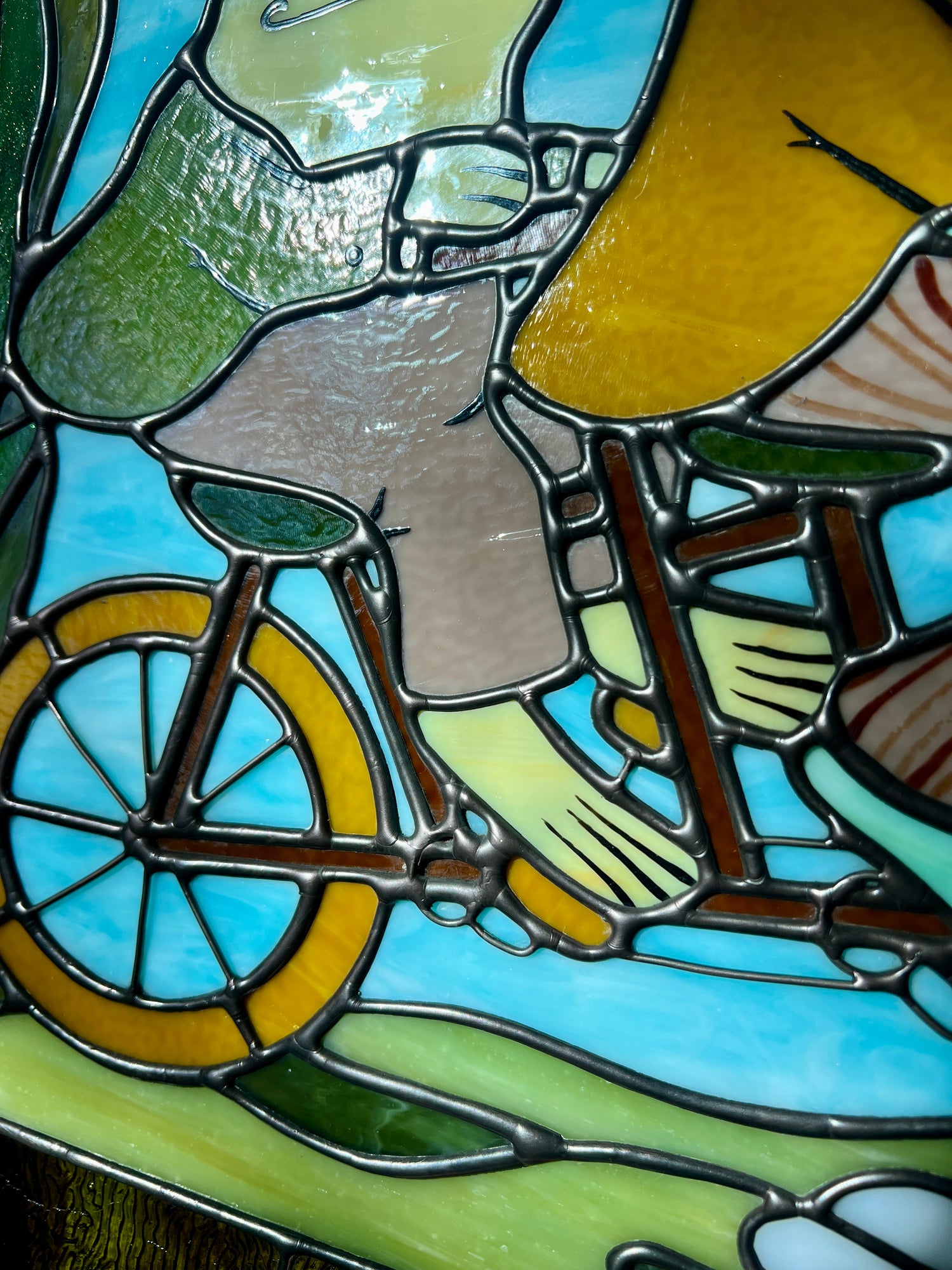close up of a stained glass panel depicting frog and toad riding a bicycle 