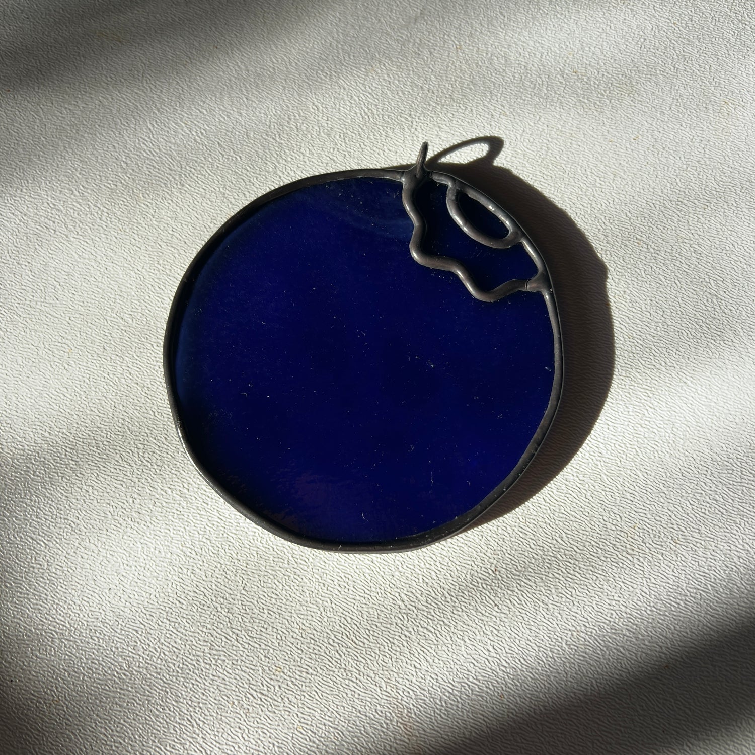 a stained glass blueberry resting on a white surface