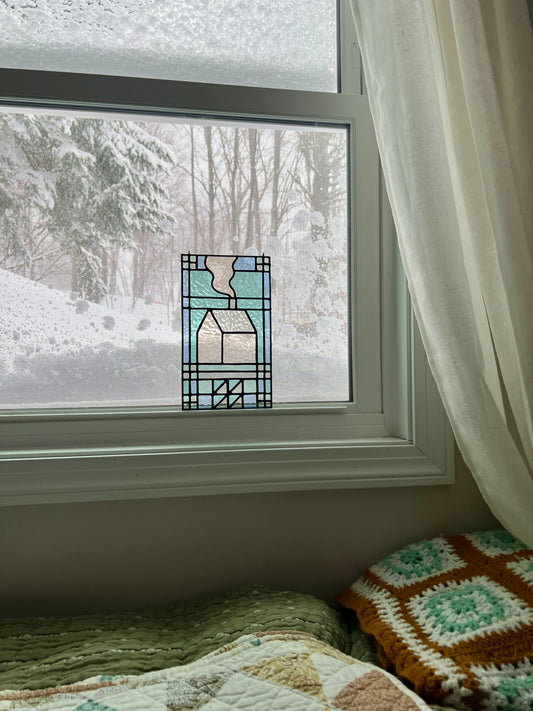 textile inspired stained glass sitting in the window of a cozy bedroom